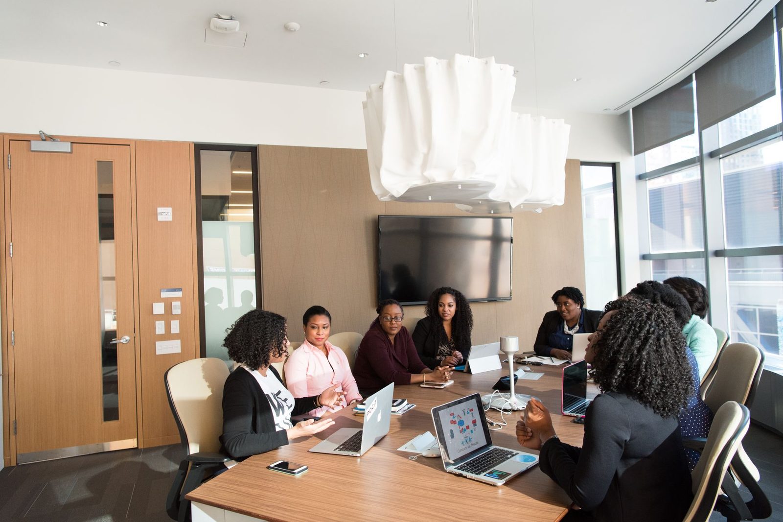 A team of colleagues talking around a table in a modern office, papers and laptops in front of them