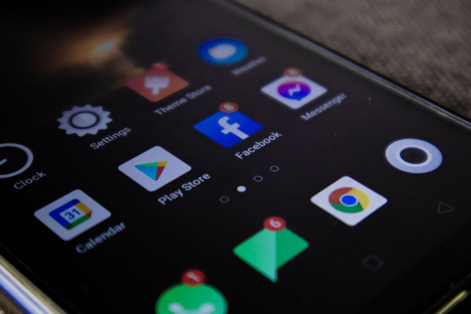 A phone screen at an angle covered in app icons, several with unread notification badges, including Messenger, Facebook and a calendar