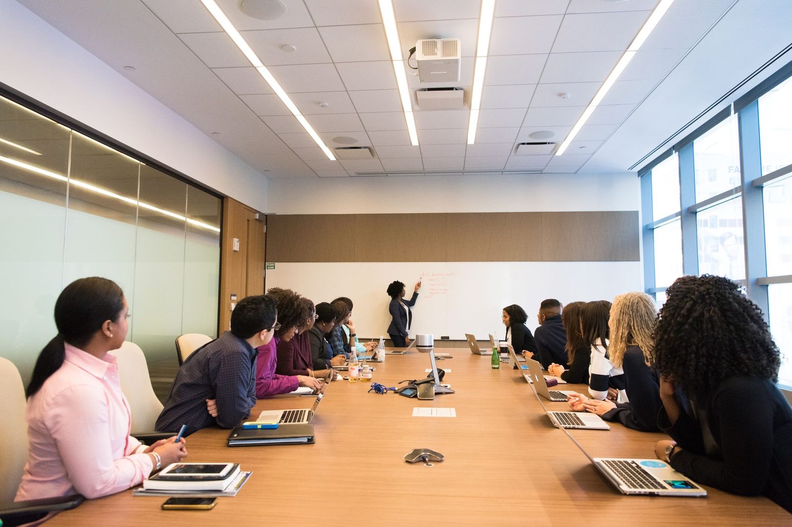 A long conference table lined with attendees in a full meeting room