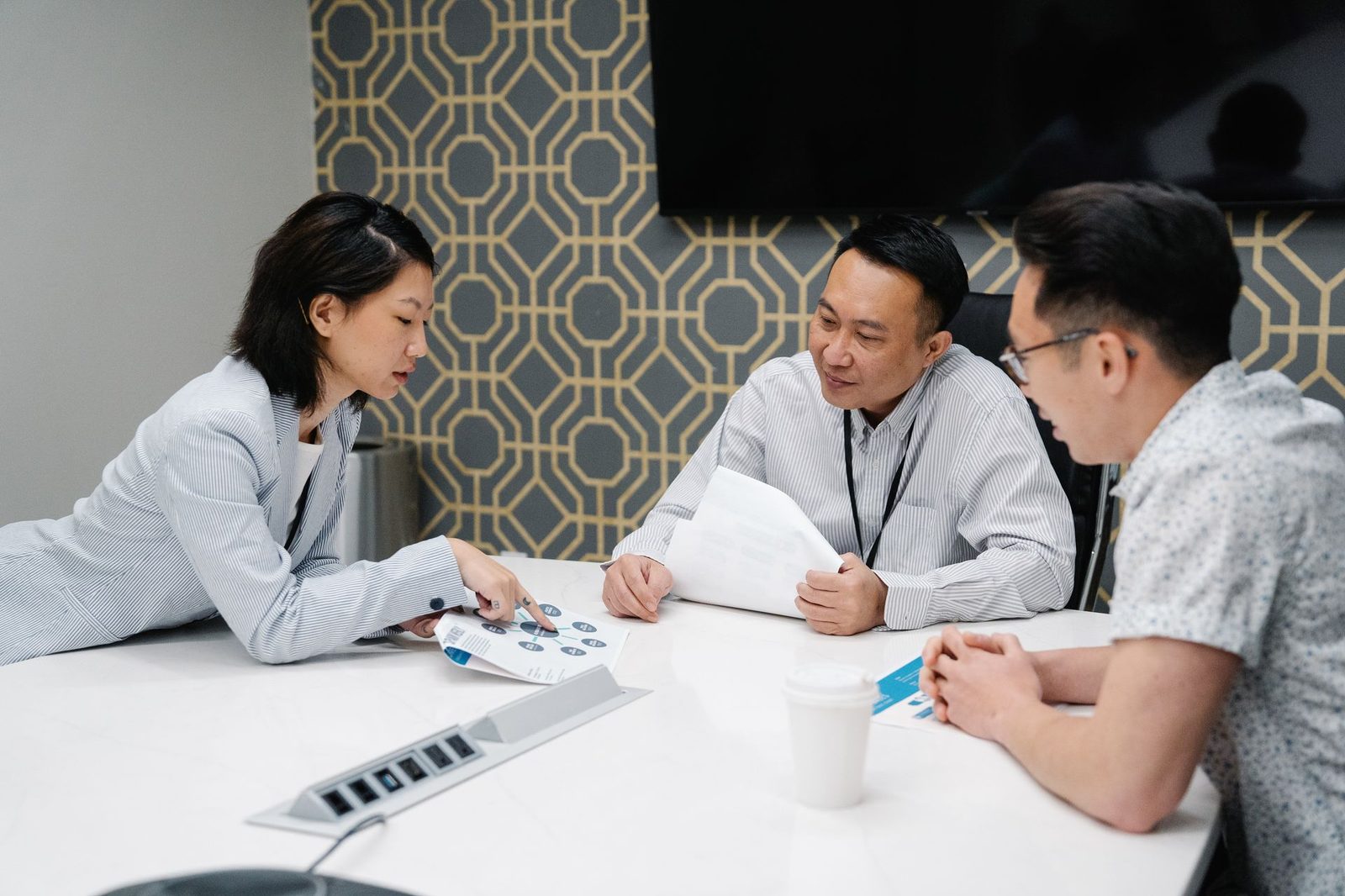 A group of colleagues in discussion around a desk in a bright office