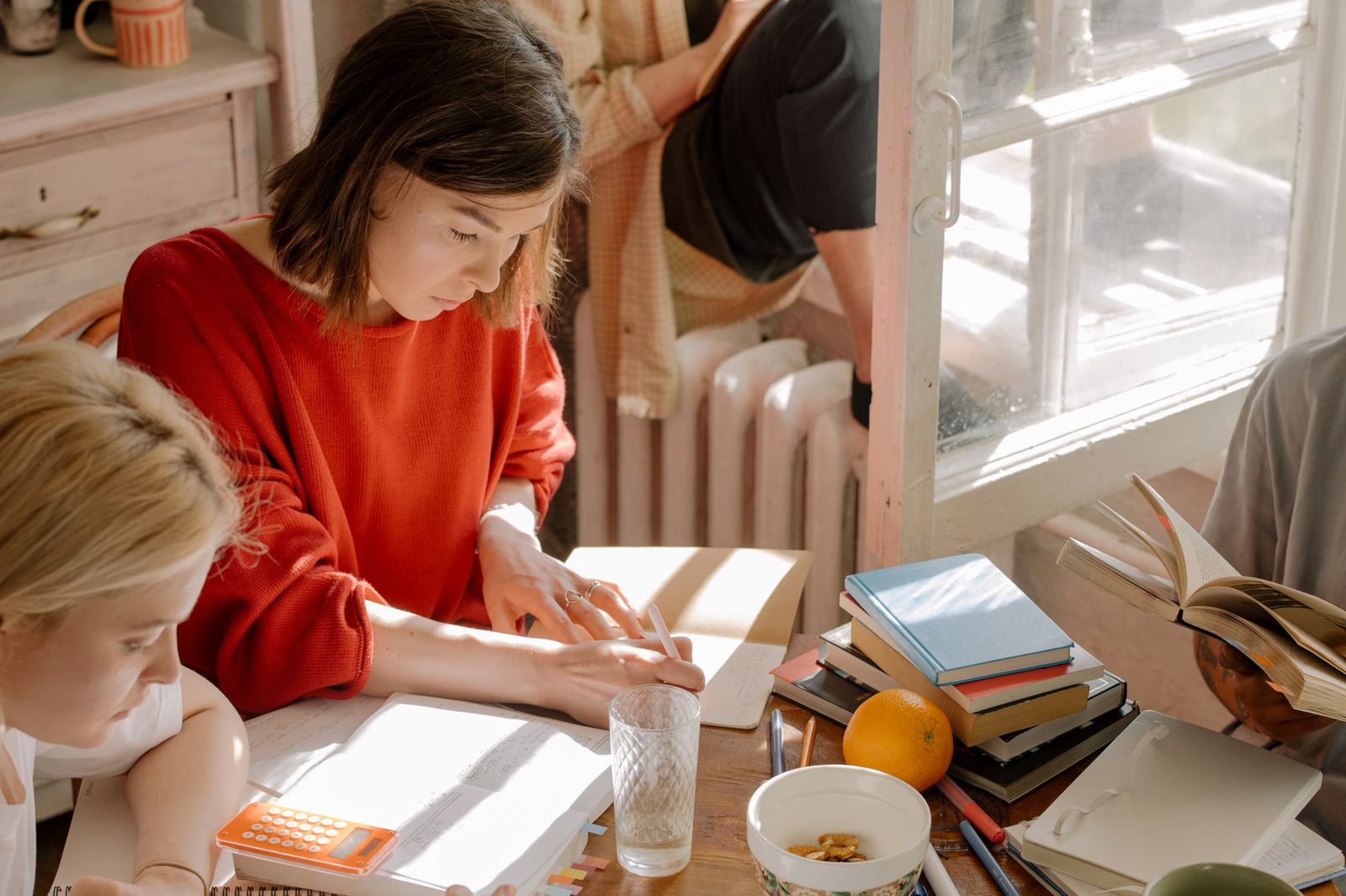 A group of people gathered closely around a table covered in notebooks, a calculator and a shared meal