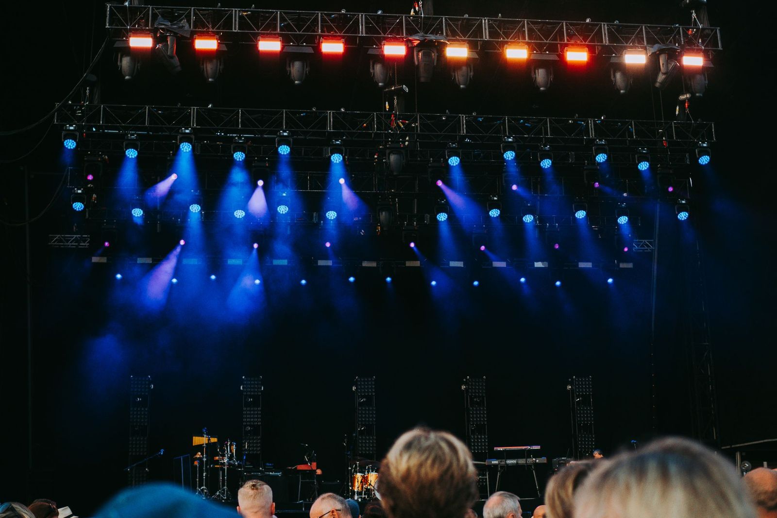 A concert-style bank of stage lights blasting overlapping blue beams down over a crowd, too many sources firing at once to focus on any one