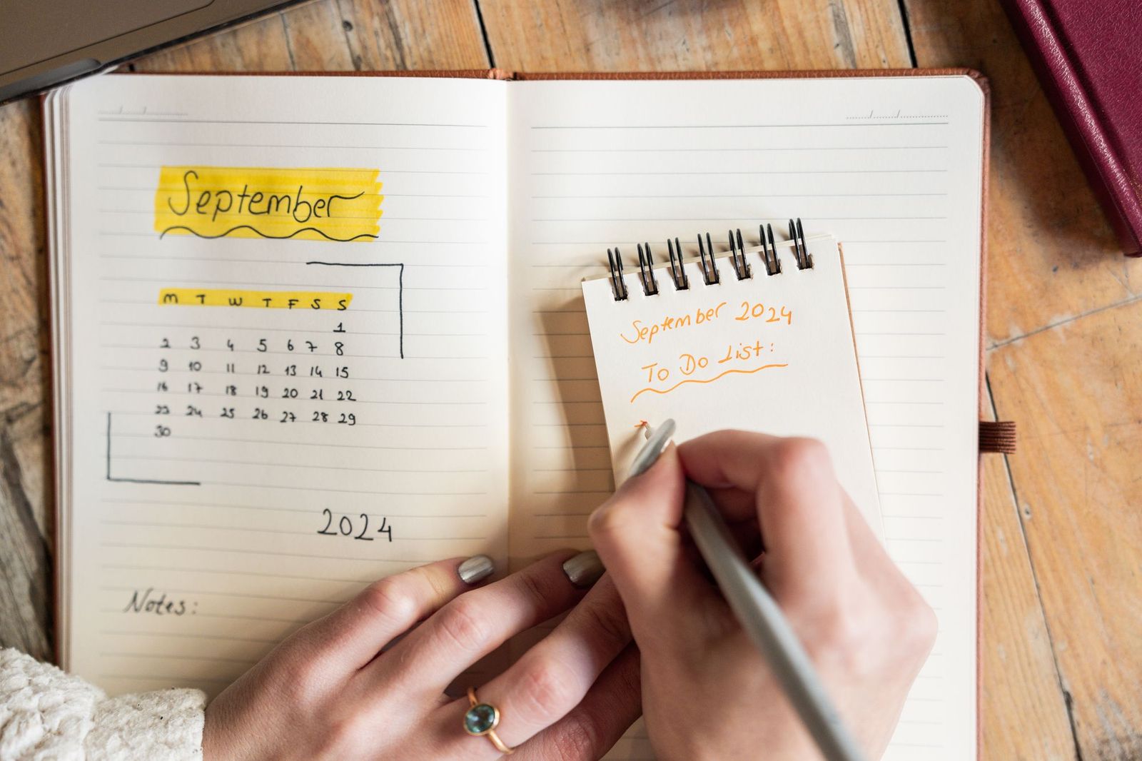 An open planner showing a September calendar page next to a spiral notepad with a handwritten to-do list